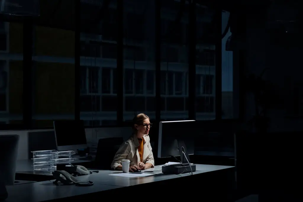 Young businesswoman using computer in dark office.